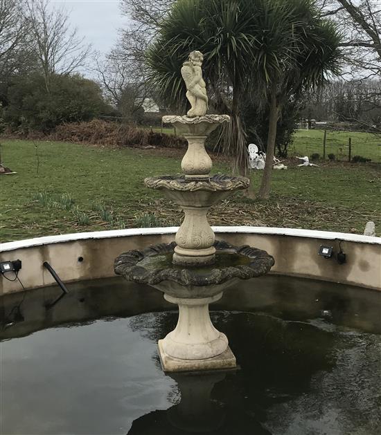 A reconstituted stone three tier garden fountain, surmounted by a putti holding a dolphin